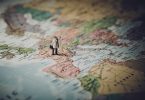 Miniaturfigur mit Aktentasche steht auf einer Weltkarte (Praktikum im Ausland)