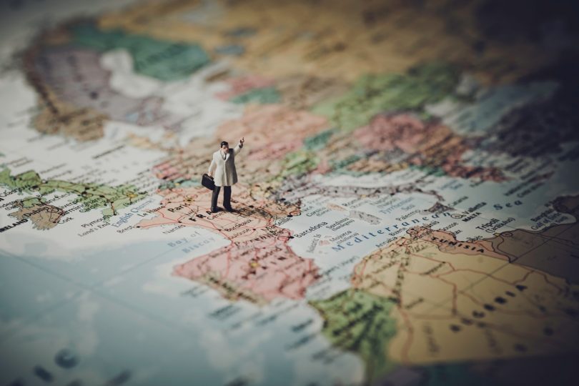 Miniaturfigur mit Aktentasche steht auf einer Weltkarte (Praktikum im Ausland)